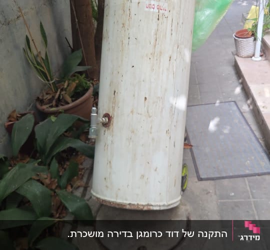 אדם מחזיק דוד שמש ישן בחצר